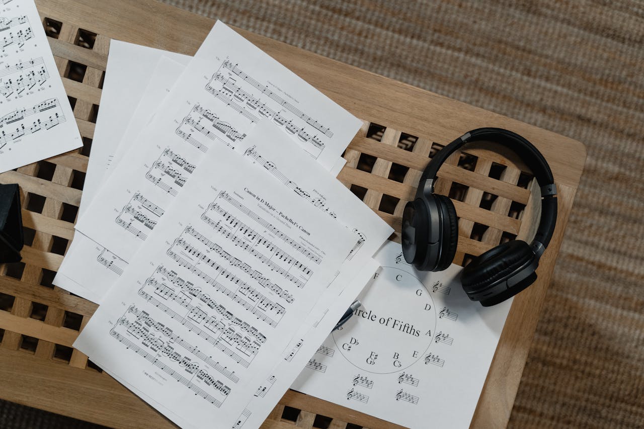 Music sheets and headphones arranged on a wooden surface, perfect for musical inspiration.