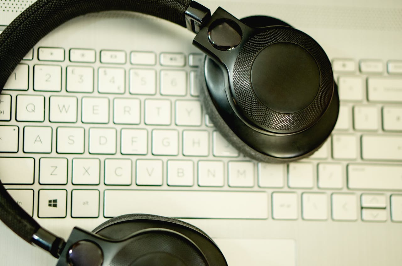 Close-up of black headphones resting on a laptop keyboard, captured from above.